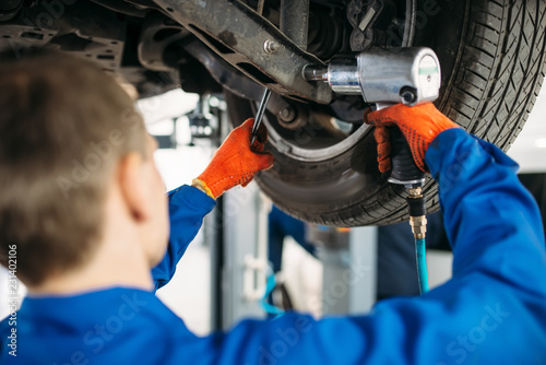 Technician with a wrench repair car suspension