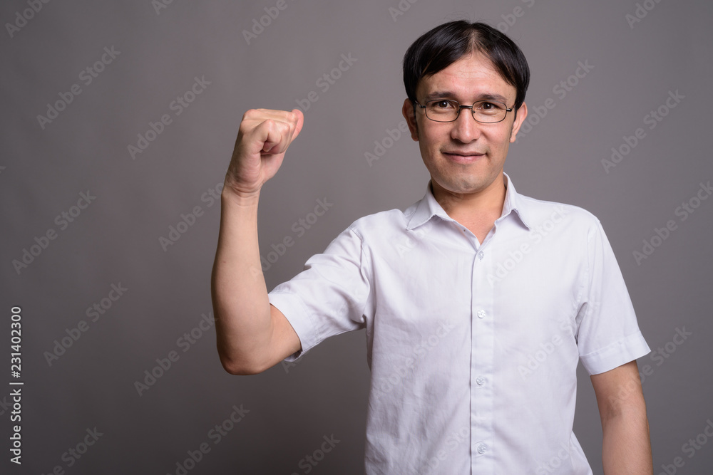 Young Asian nerd man wearing eyeglasses against gray background Young Asian nerd man wearing eyeglasses against gray background