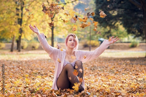 Young woman throws fall leaves in park