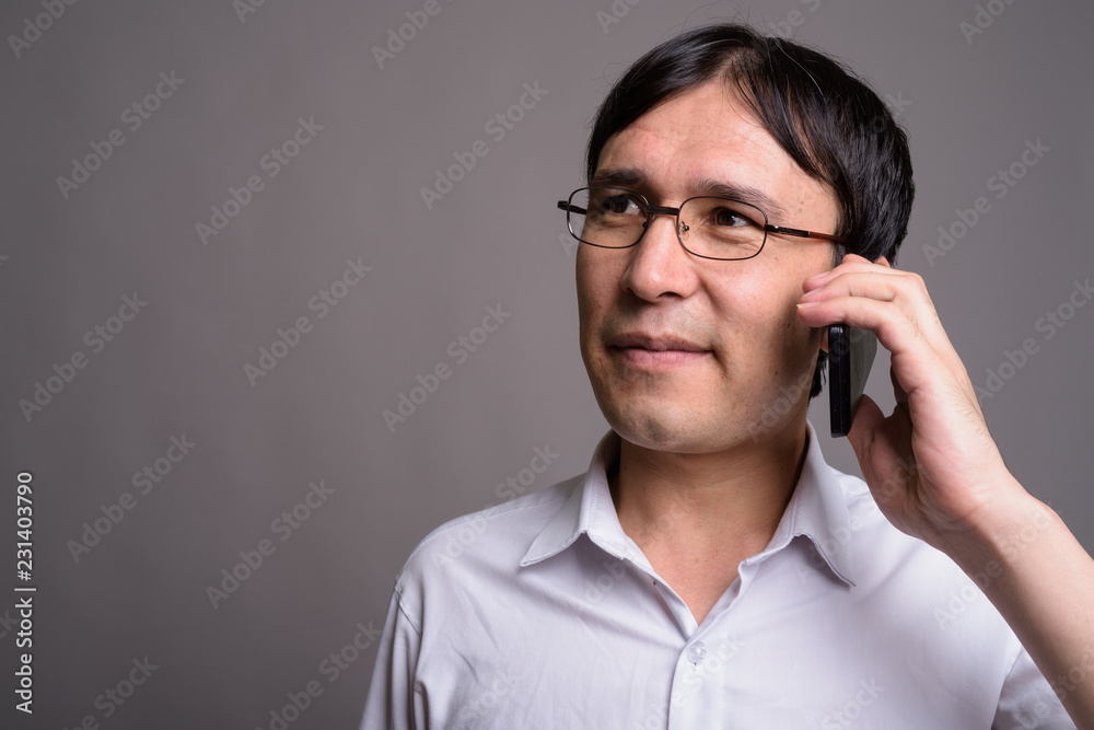 Young Asian nerd man wearing eyeglasses against gray background Young Asian nerd man wearing eyeglasses against gray background