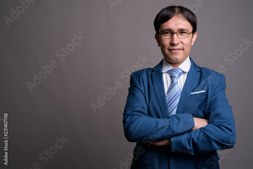 Portrait of young Asian businessman against gray background