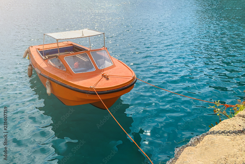 Obraz premium Small orange motor boat in a turquoise sea water, toned