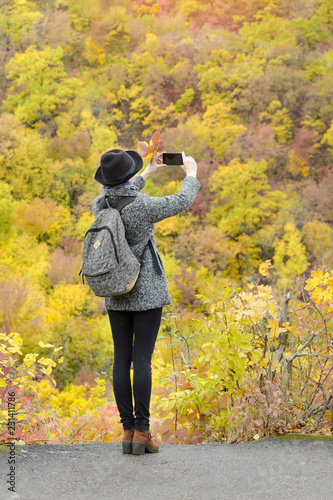Girl with mobile phone pictures of the autumn forest. Back view © somemeans