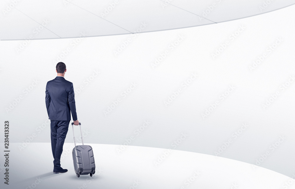 Obraz premium Businessman with back walking in a white waiting room with empty walls around 