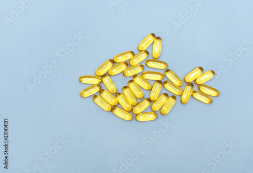 top view on vitamins for health, yellow fish oil capsules, omega in the form of fish on a light blue background with space for text. Medications.
