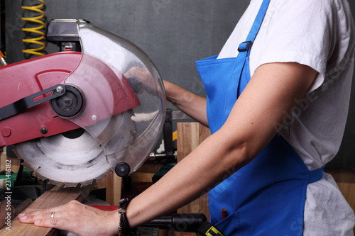 Woman cutting a piece of wood with a mitter saw