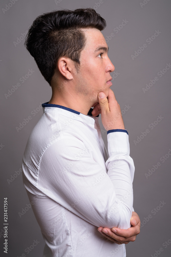 Portrait of young Asian businessman against gray background Portrait of young Asian businessman against gray background