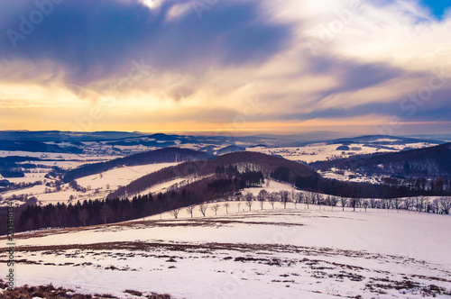 Majestic winter landscape with snow and dramatic sky in Rhön Mountains, Germany