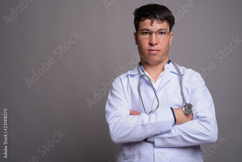 Young Asian man doctor against gray background © Ranta Images