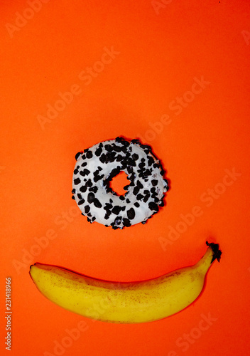 Banana and donut on orange background