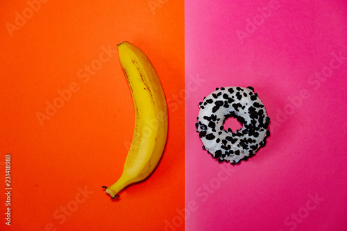 Banana and donut laying on orange and pink backgrounds