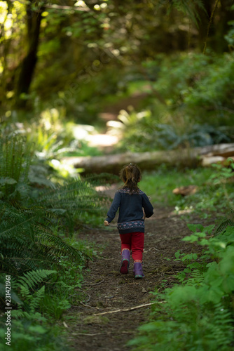 little girl running in the lush green forest