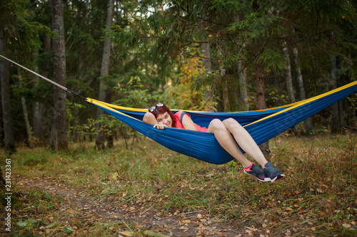 Photo of young woman lying in hammock in woods