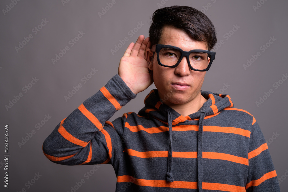 Fototapeta premium Young Asian nerd man wearing hoodie against gray background