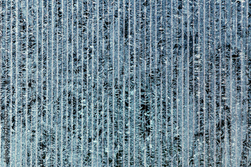 Frosty pattern of hoarfrost and snowflakes on striped glass, winter or Christmas background, texture