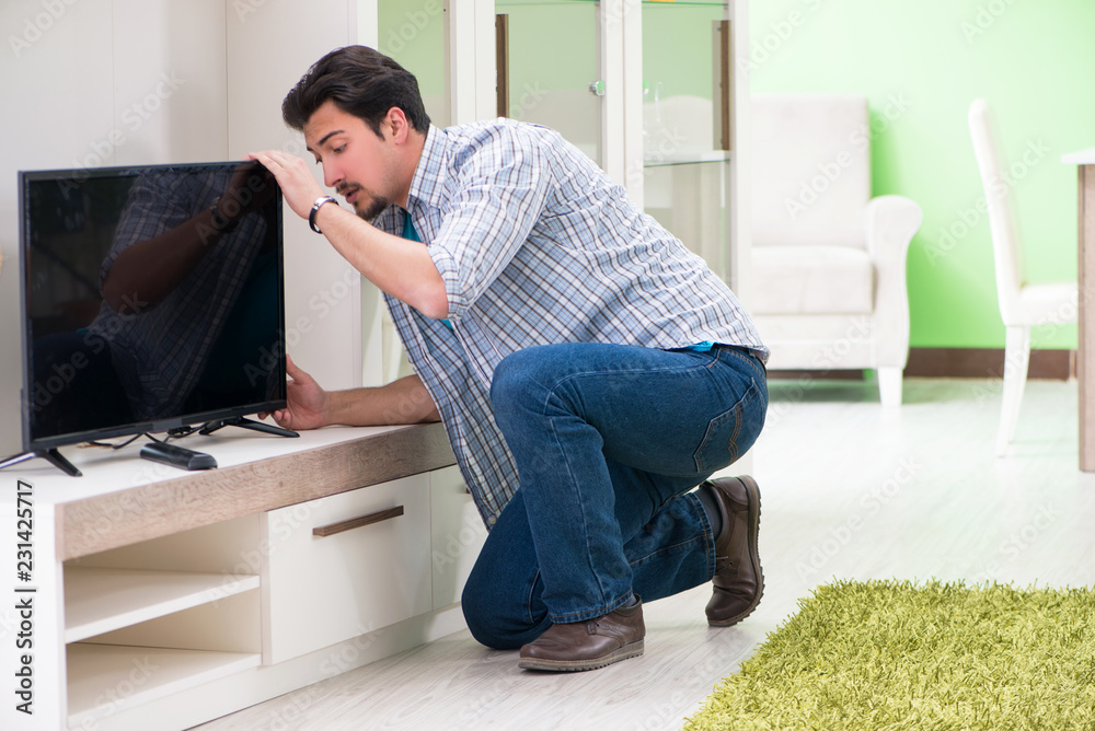 Young man husband repairing tv at home 