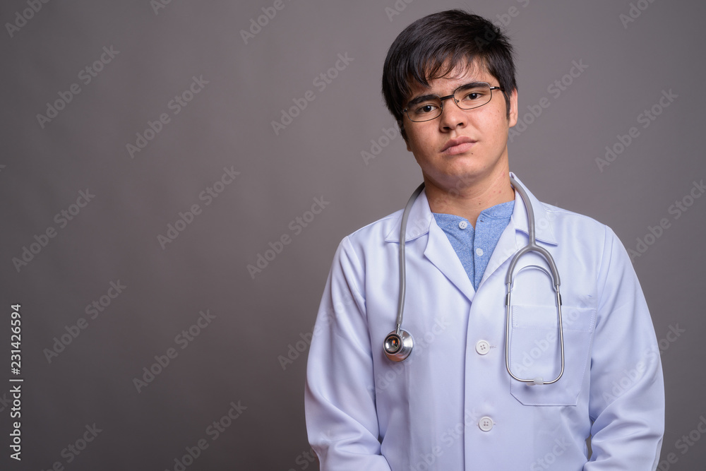 Young Asian man doctor against gray background Young Asian man doctor against gray background
