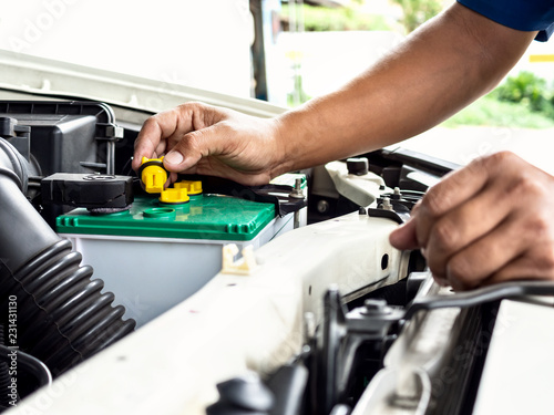 Technician hand opening the car battery for checking, repair or filling new distilled water in garage at car auto service for maintenance electrical system of the car.