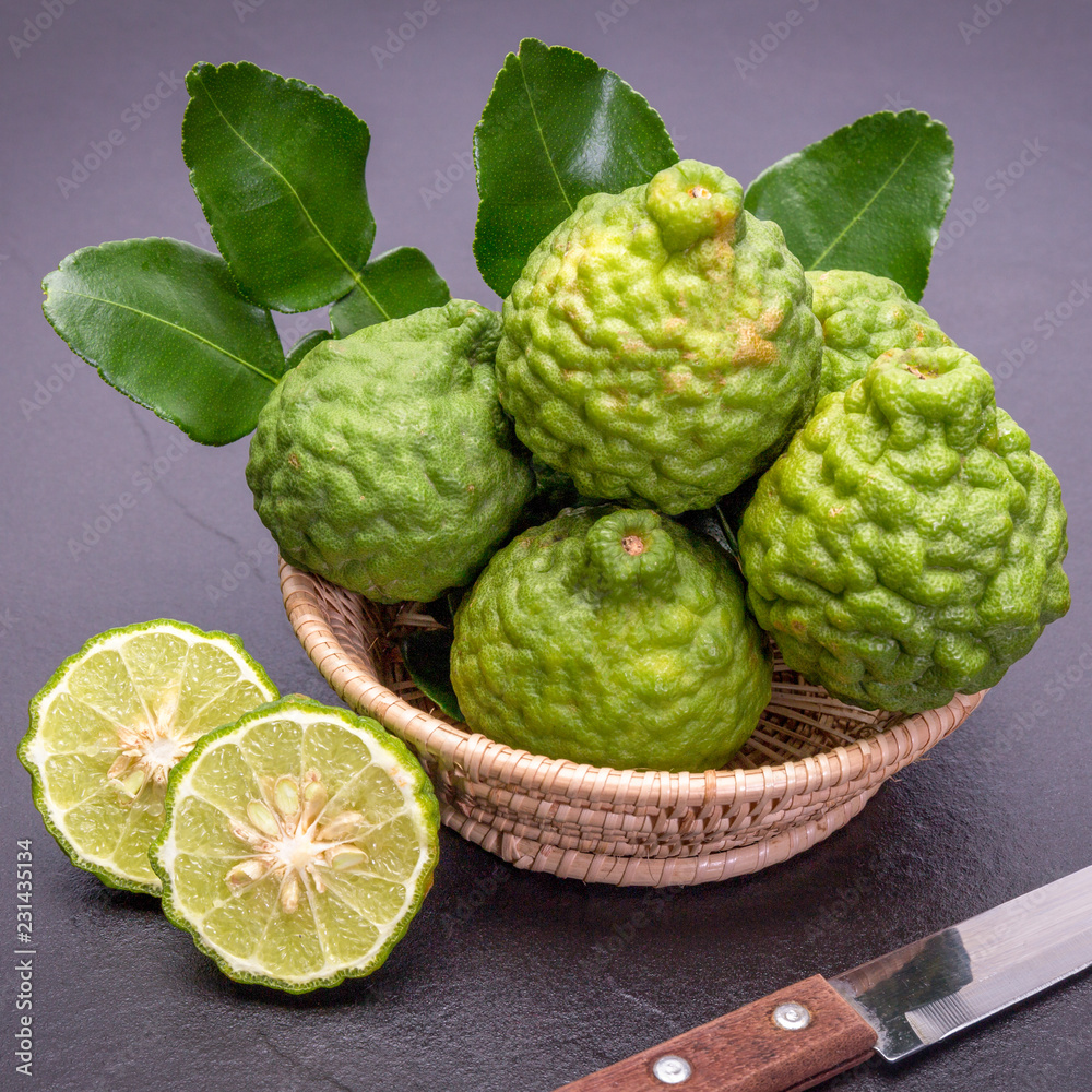 Bergamot, kaffir lime and kaffir lime leaf with basket and knife on dark background Bergamot, kaffir lime and kaffir lime leaf with basket and knife on dark background