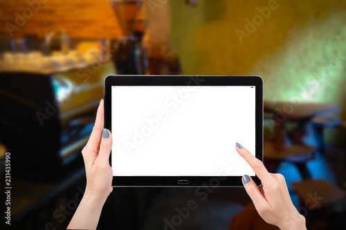 Hand using mock up computer tablet on coffee shop cafe background, with copy space