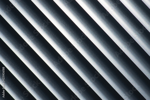 An abstract look at metal blinds with a diagonal tilt, with emphasis on highlights and shadows.