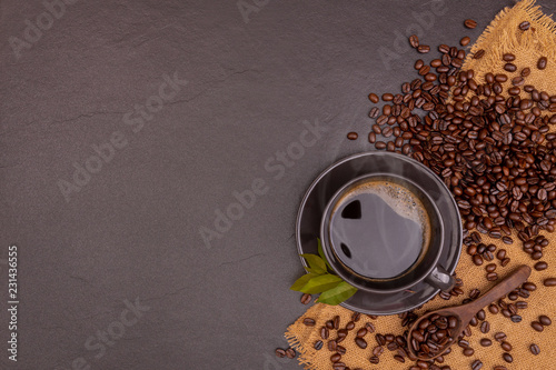 A black coffee in cap with beans and leaves on the black stone with sackcloth, for weight loss good health. copy space