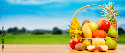 Fototapeta Naklejka Na Ścianę i Meble -  Composition with assorted fruits in wicker basket on wooden table, copy space