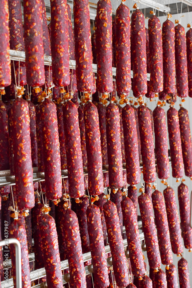 Dried sausage hanging on a rope on a metal frame in the smoke house