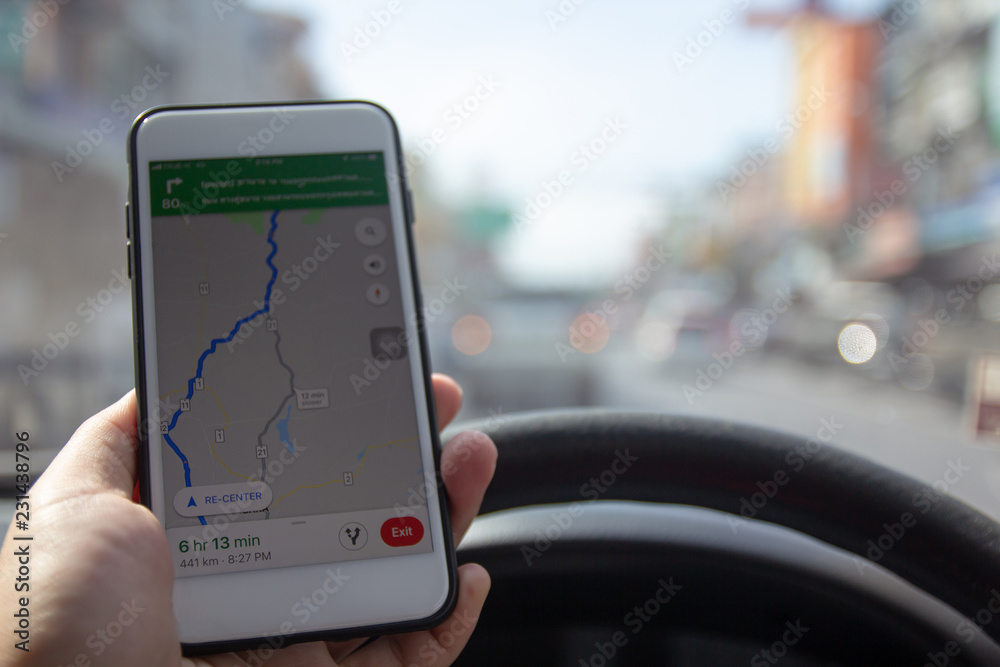 Man driving car and holding mobile phone with map gps navigation.