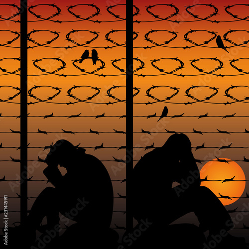 Migrant refugees behind barbed wire, silhouette of two sad men sitting on the ground, against the background of an orange sunset,