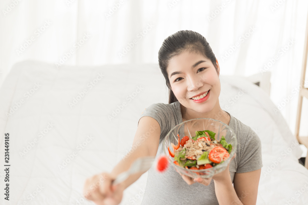 Enjoyed Asian woman eating vegetable salad.