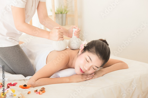 Young asain woman getting herbal compress massage in spa salon. alternative medicine and relaxation Concept.