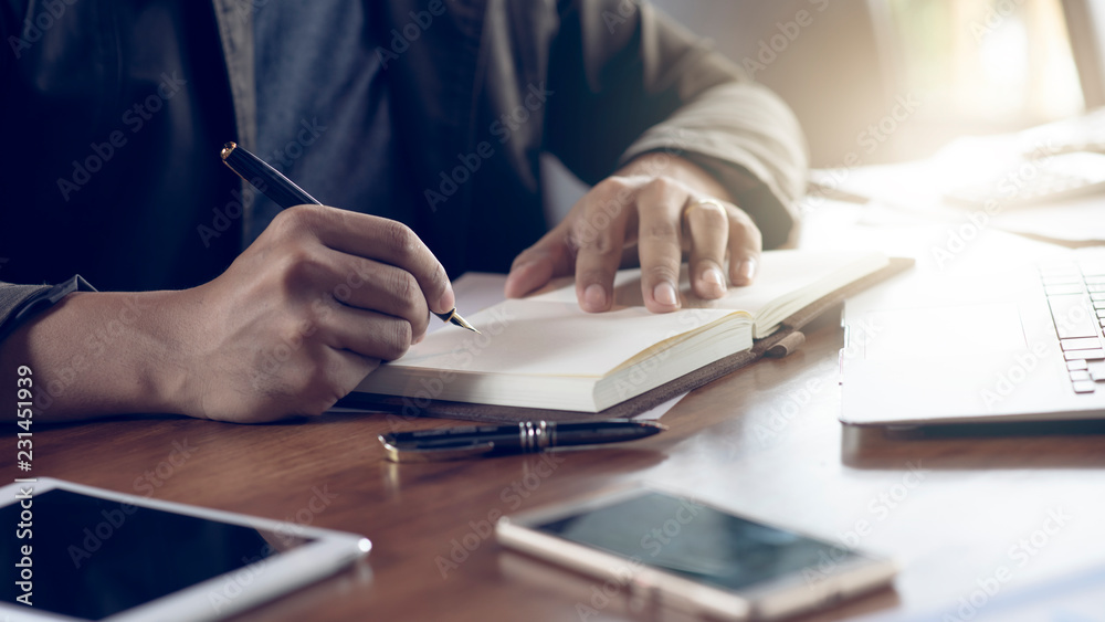 Hands of a male businessman signing a contract in an office. Hands of a male businessman signing a contract in an office.