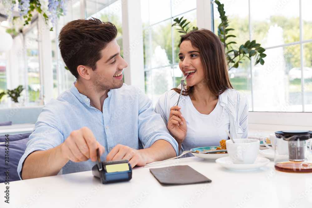Happy loving couple sitting in cafe holding credit card and make payment. Happy loving couple sitting in cafe holding credit card and make payment.