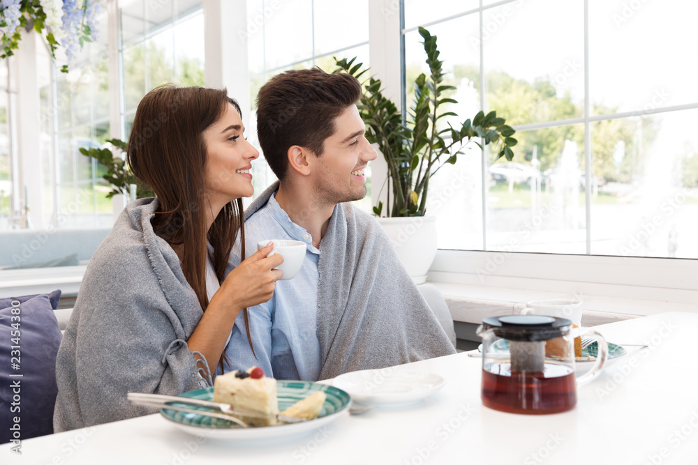 Loving couple sitting in cafe eat desserts and drinking tea.