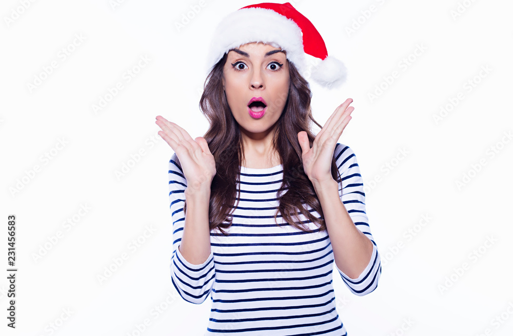 Wow face of young attractive woman in santa hat posing on white background Wow face of young attractive woman in santa hat posing on white background