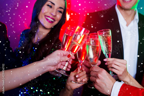 Close view of clinking glasses of sparkling champagne, big company of friends on the christmas or new year perty is celebrating together photo