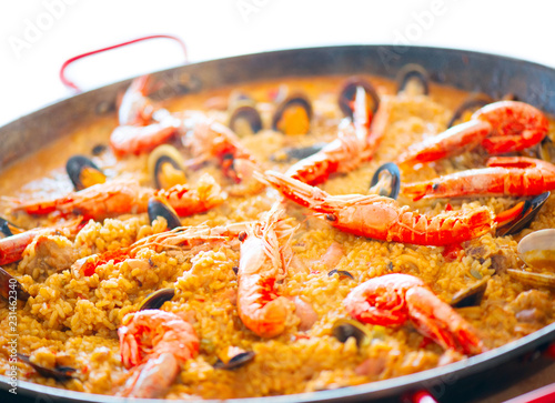 Paella. Traditional spanish food, seafood paella in the fry pan with mussels, king prawns, langoustine and squids isolated on white. Cooking paella