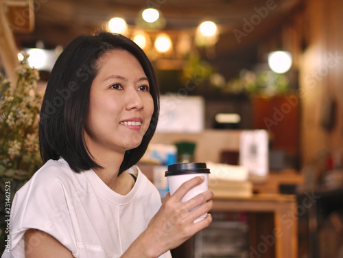 Wallpaper Mural Portraits of Asian woman holding a cup of coffee looking to her left hand with smile face in cozy coffee shop. Torontodigital.ca
