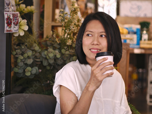 Wallpaper Mural Portraits of Asian woman holding a cup of coffee looking to her right hand with smile face in cozy coffee shop. Torontodigital.ca