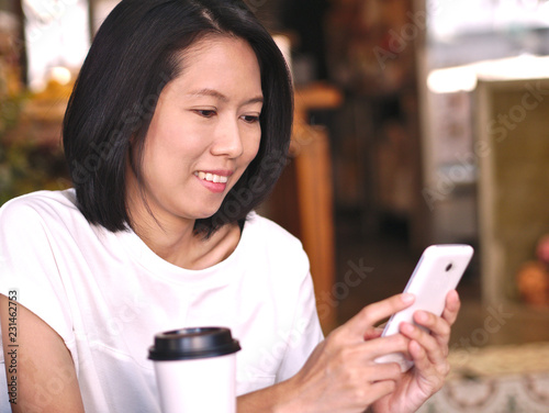 Wallpaper Mural Portraits of Asian woman typing to her smartphone screen with smile happy face with one cup of coffee in cozy coffee shop. Torontodigital.ca