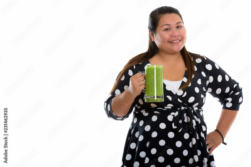 Studio shot of young happy fat Asian woman smiling while holding Studio shot of young happy fat Asian woman smiling while holding