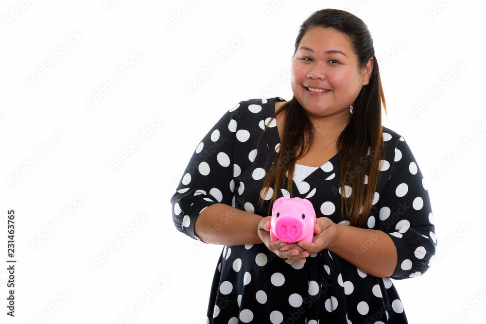 Studio shot of young happy fat Asian woman smiling while holding Studio shot of young happy fat Asian woman smiling while holding