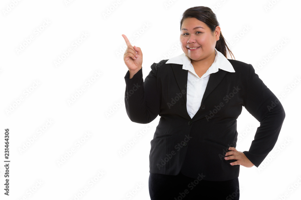 Studio shot of young happy fat Asian businesswoman smiling and p Studio shot of young happy fat Asian businesswoman smiling and p