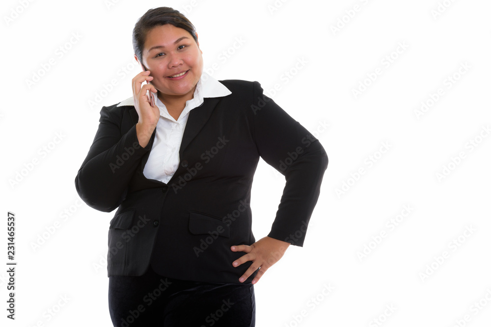 Studio shot of young happy fat Asian businesswoman smiling while Studio shot of young happy fat Asian businesswoman smiling while