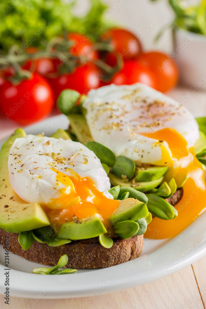 Avocado toast, cherry tomato and poached eggs on wooden background. Breakfast with vegetarian food, healthy diet concept. Avocado toast, cherry tomato and poached eggs on wooden background. Breakfast with vegetarian food, healthy diet concept.