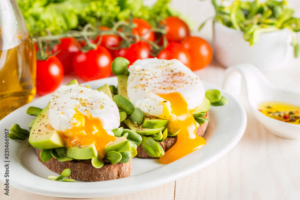 Avocado toast, cherry tomato and poached eggs on wooden background. Breakfast with vegetarian food, healthy diet concept. Avocado toast, cherry tomato and poached eggs on wooden background. Breakfast with vegetarian food, healthy diet concept.