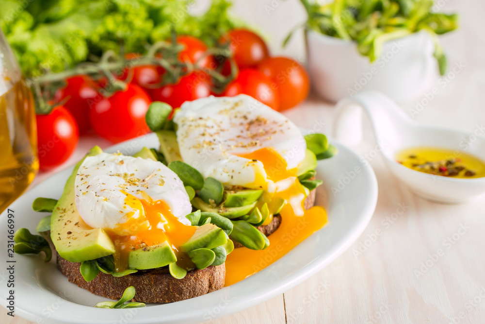 Avocado toast, cherry tomato and poached eggs on wooden background. Breakfast with vegetarian food, healthy diet concept.