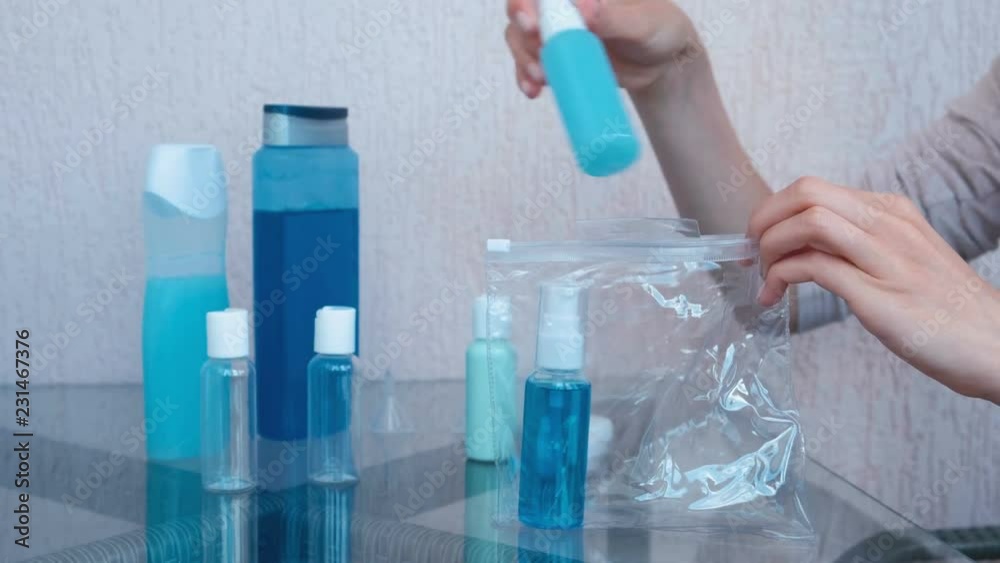 Women's hands put a road set of cosmetics with bottles and jars in a zip plastic pouch. Close-up jars. Women's hands put a road set of cosmetics with bottles and jars in a zip plastic pouch. Close-up jars.