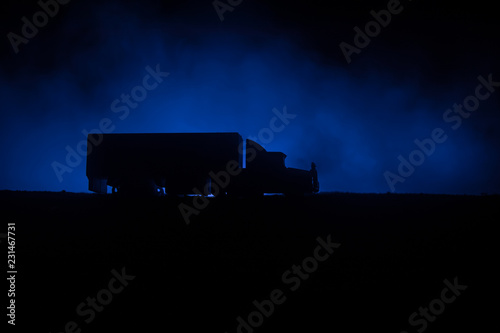 Big truck wagon rides on the road outside the city at night with foggy background. Decoration